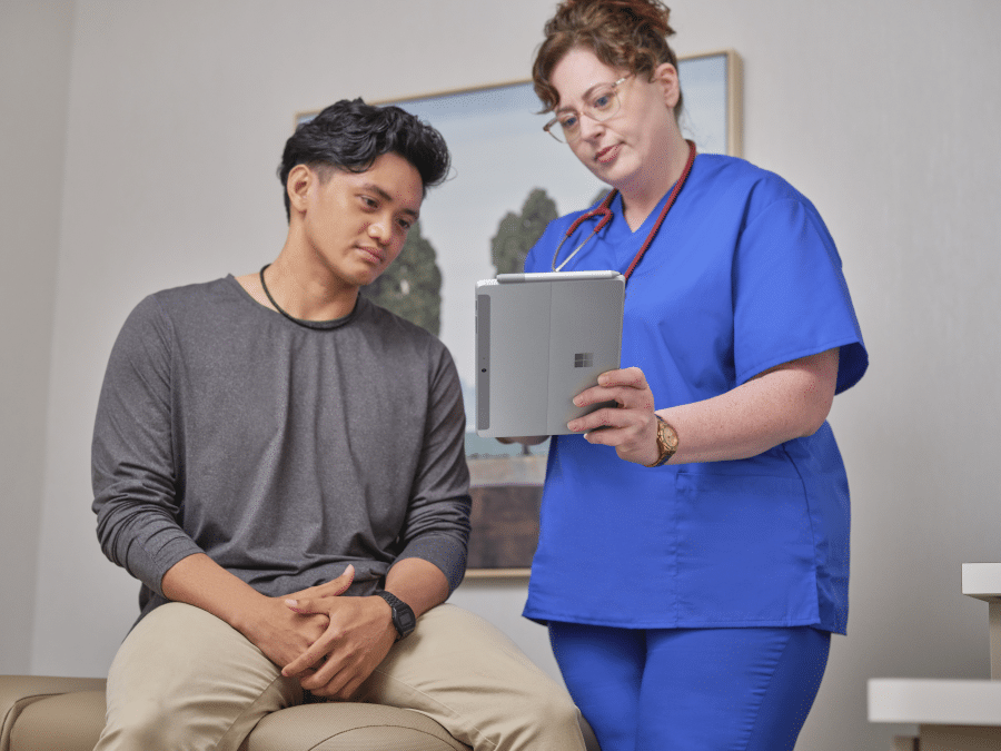 Female nurse sharing screen of a Surface Go 3 with a patient while holding a Surface Pen.