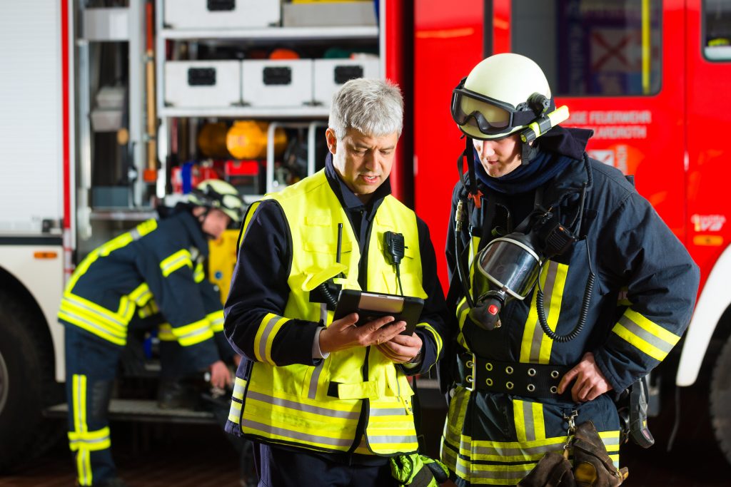 Firefighters looking at device in fire station