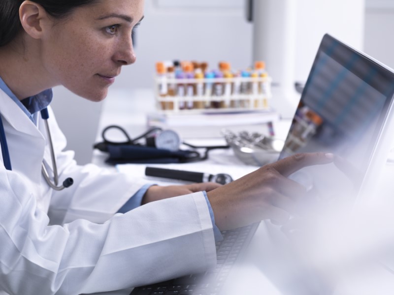 Doctor accessing a patients details using a touch screen computer in a clinic.