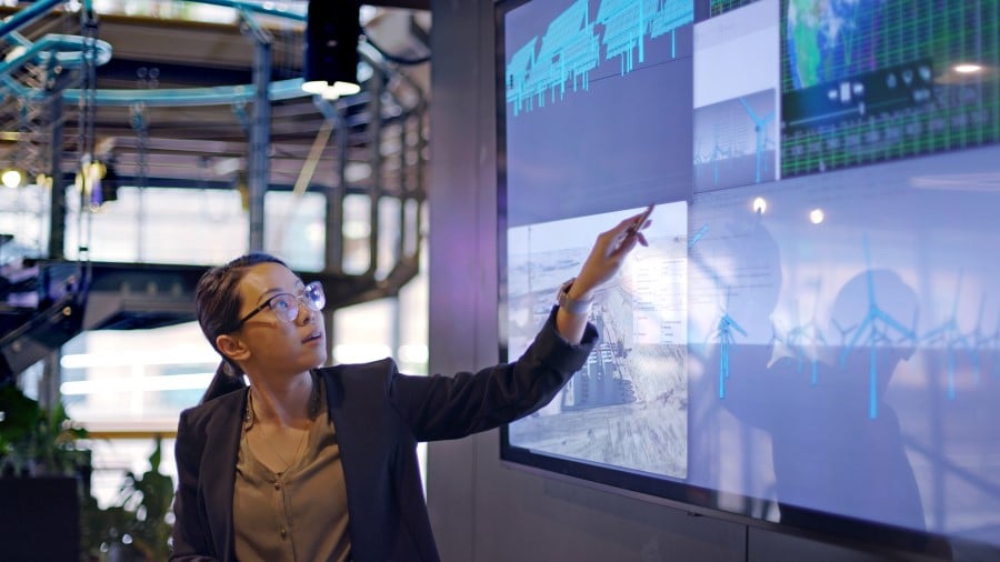 woman pointing to data and analysis on computer monitor
