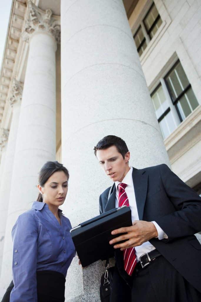 Two people looking at tablet outside of courthouse.