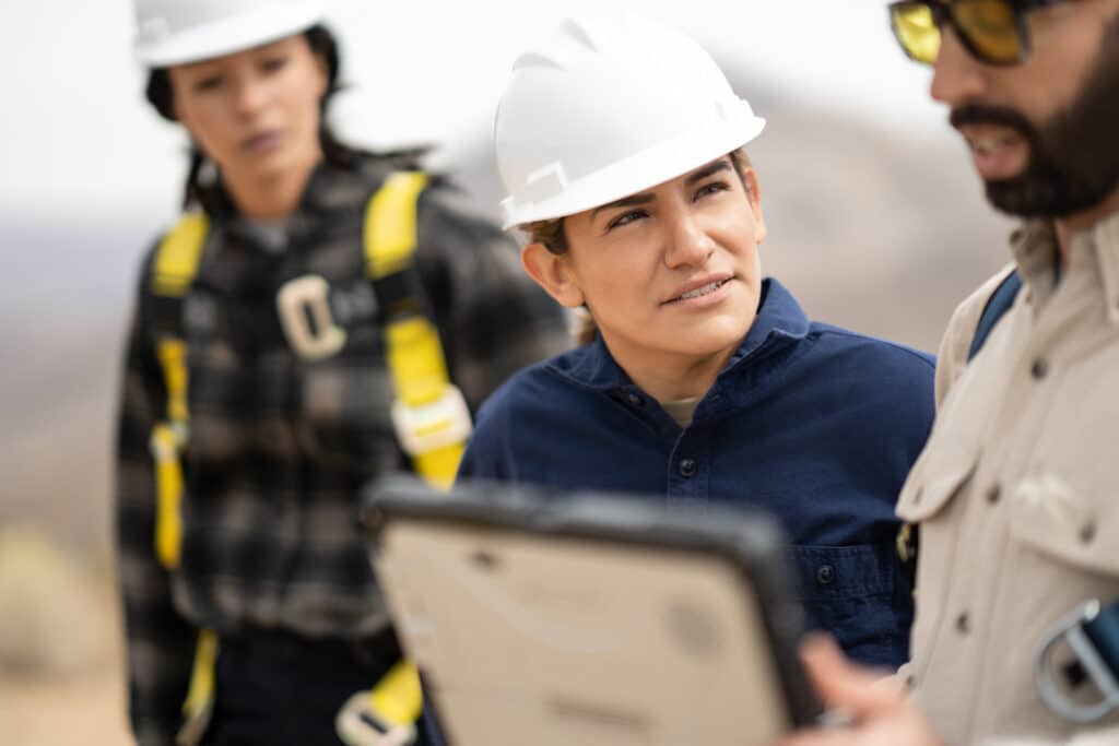 people in hard hats looking at a tablet