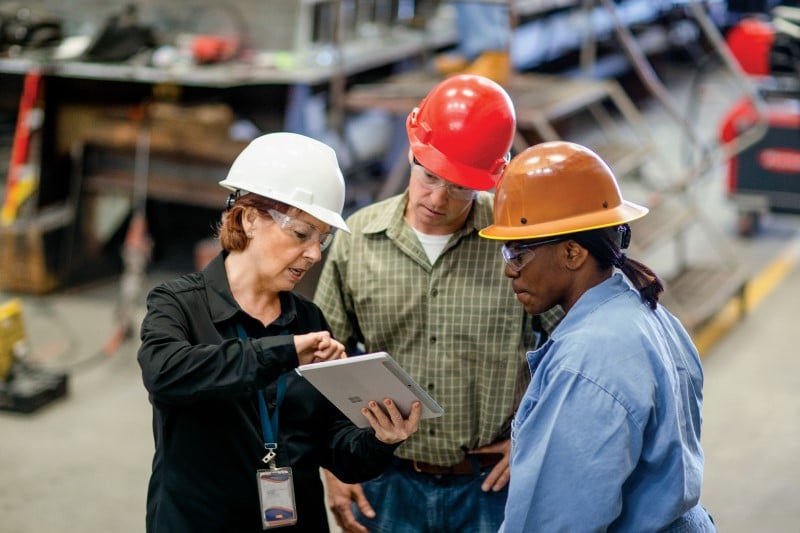 CEO of large manufacturing company discussing a project with operations manager and foreman.