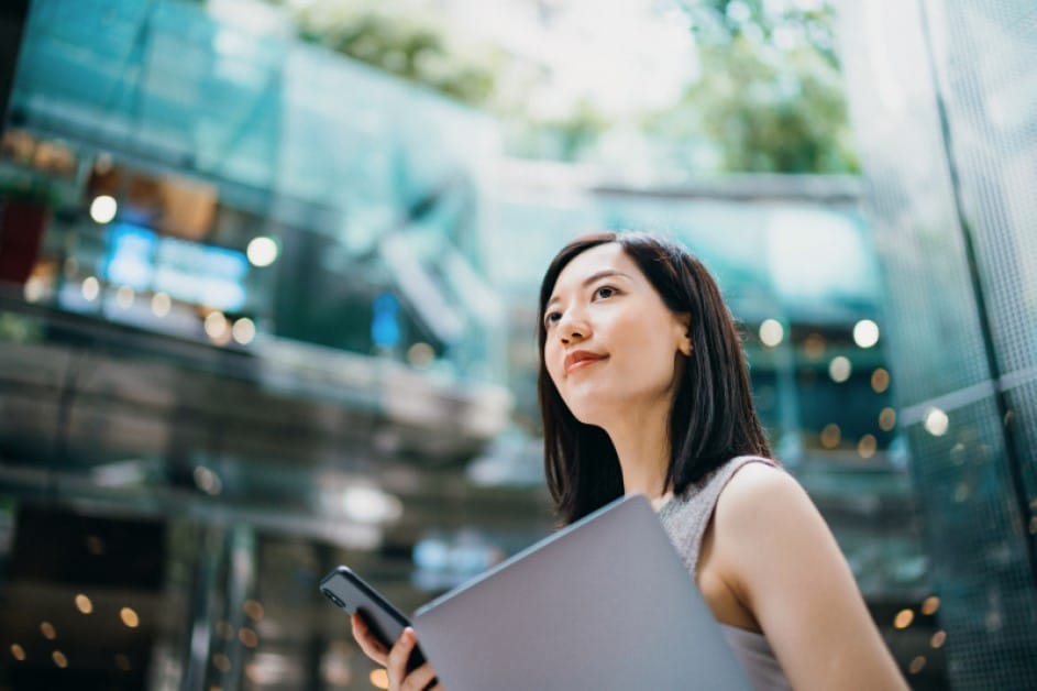 A businesswoman carries a smart phone and laptop on her commute to work in central business district.